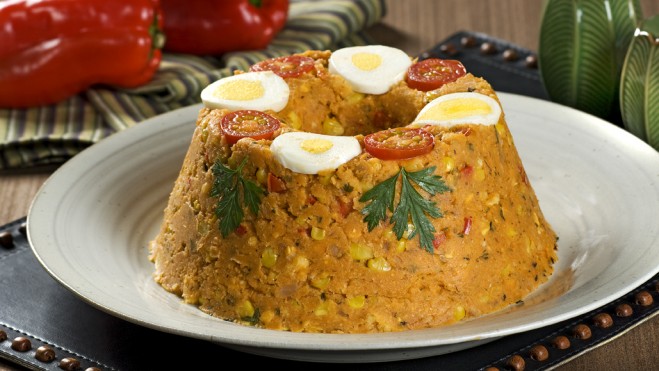 Imagem de um prato com cuscuz paulista com rodelas de tomate e ovo cozido