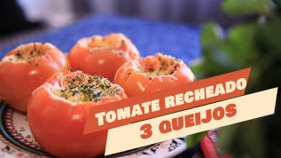 Imagem de quatro tomates recheados com três tipos de queijos e oregano por cima