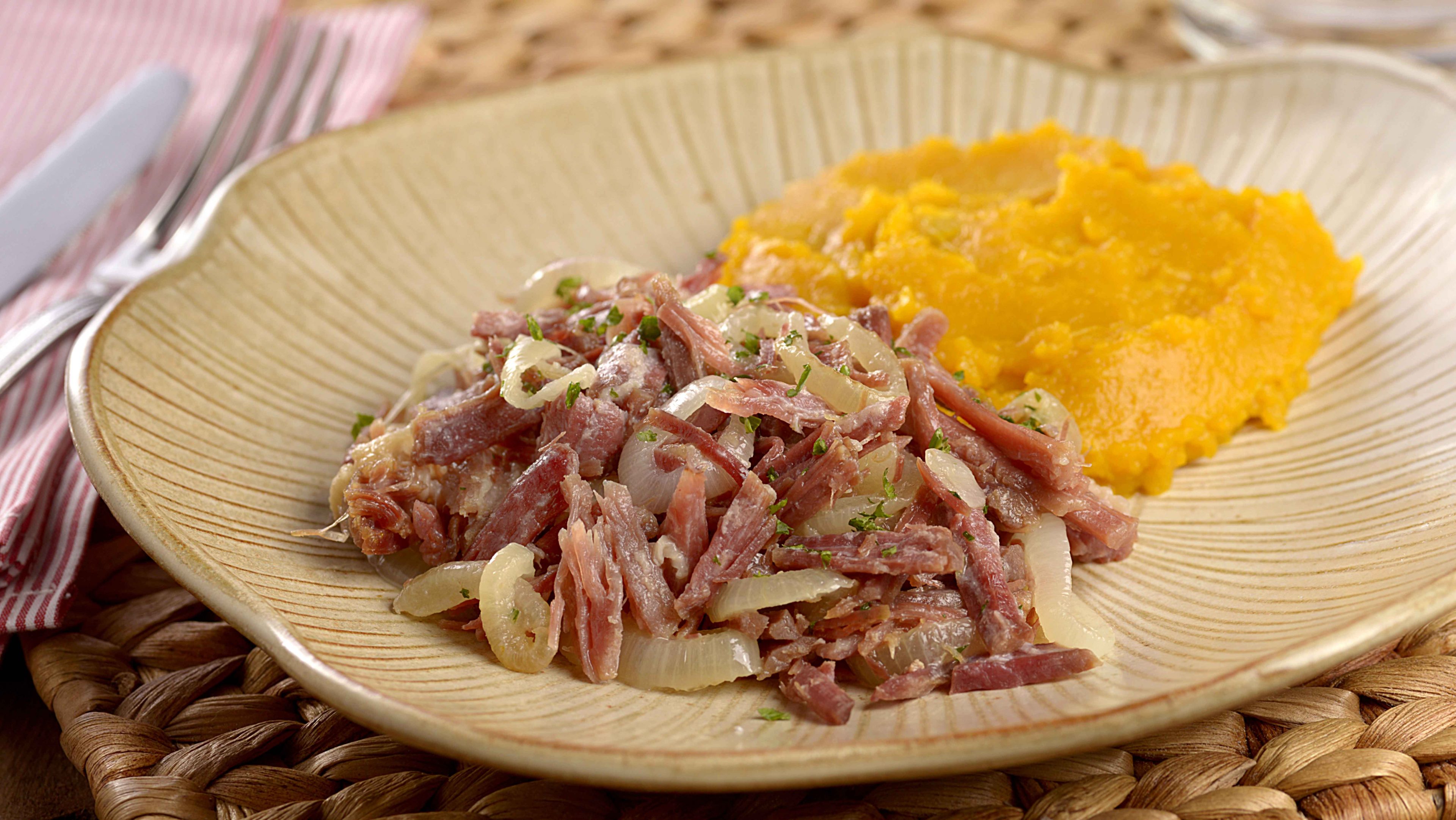 Imagem de um prato contendo tiras de Carne de Sol com cebola e polenta de acompanhamento