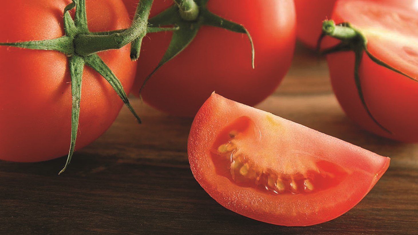 Imagem de tomates cortados em uma mesa de madeira