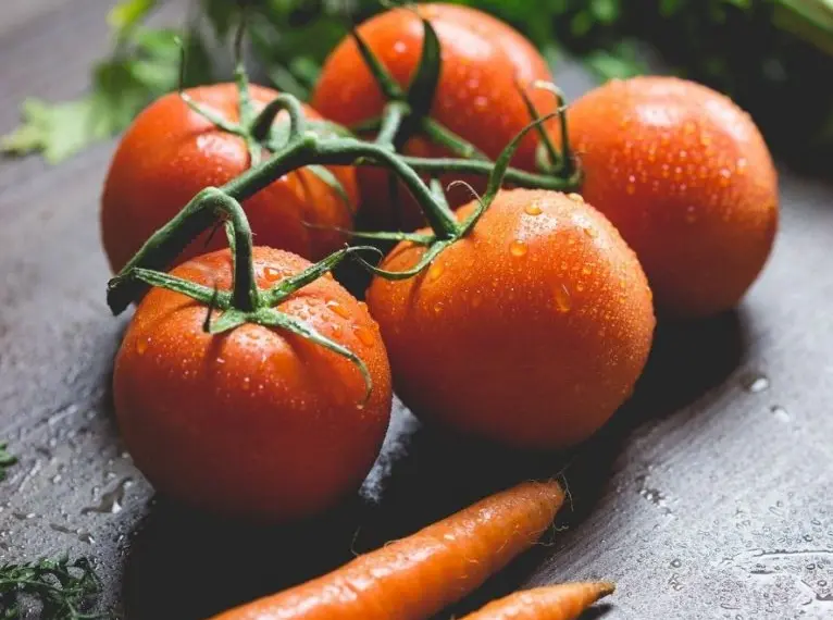 Cinco tomates em uma mesa de madeira