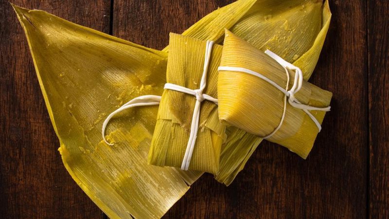 mesa com duas Pamonhas doce em cima da palha do milho